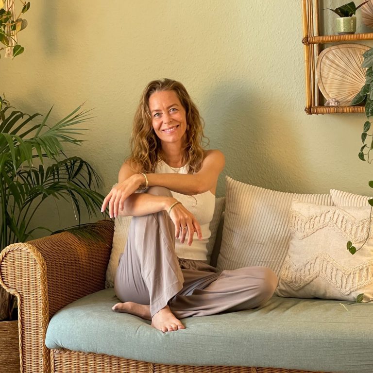 Svenja Eschenburg sitzt auf einem Sofa und lächelt in die Kamera.